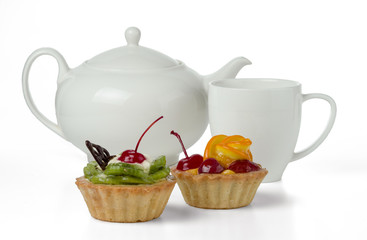 Colorful fruit cakes made with kiwi, orange, candied cherry, cream and chocolate isolated on a white background with a cup and a teapot.