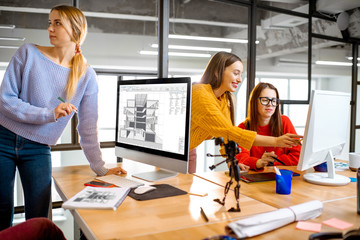 Group of a young coworkers working together on architectural project with computers in the modern office