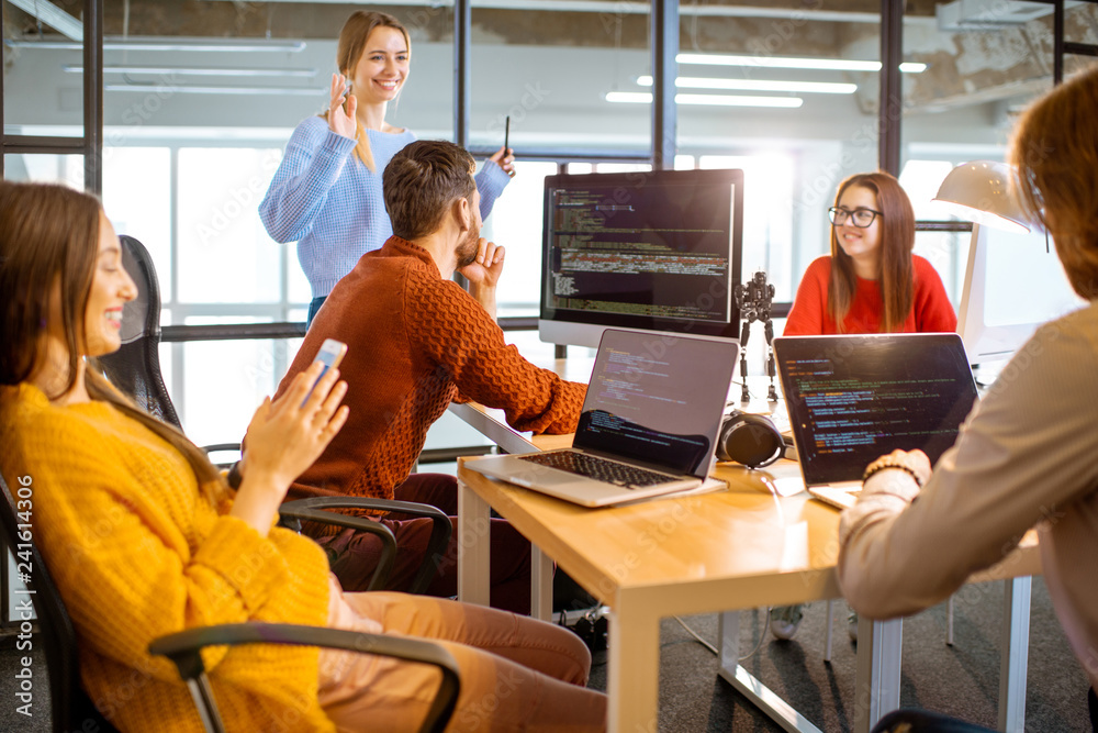 Wall mural team of a young programmers dressed casually working on computer code sitting in the modern office i