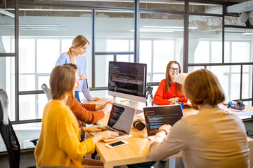 Team of a young programmers dressed casually working on computer code sitting in the modern office...