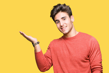 Young handsome man over isolated background smiling cheerful presenting and pointing with palm of hand looking at the camera.