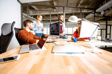 Group of young coworkers dressed casually working together on the computers in the modern office interior