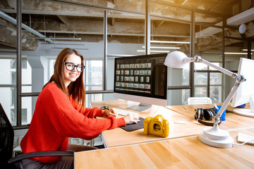 Portrait of a woman working as a photographer editing photos with computer at the working place in the modern office interior