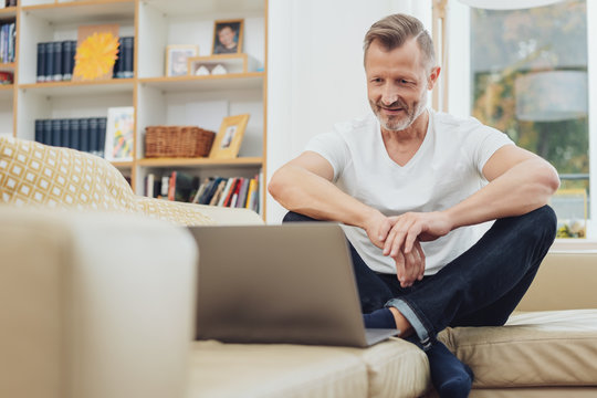 Man sitting on couch and looking at laptop