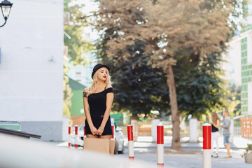 blond attractive girl in a hat after shopping in the rays of the summer sun