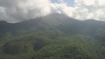 Aerial view of mountains covered forest, trees in cloudy weather, Bulusan Volcano. Luzon, Philippines. Slopes of mountains with evergreen vegetation. Mountainous tropical landscape.