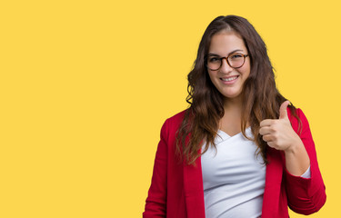 Fototapeta premium Beautiful plus size young business woman wearing elegant jacket and glasses over isolated background doing happy thumbs up gesture with hand. Approving expression looking at the camera