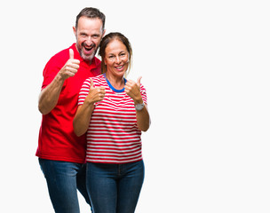 Middle age hispanic couple in love over isolated background success sign doing positive gesture with hand, thumbs up smiling and happy. Looking at the camera with cheerful expression, winner gesture.