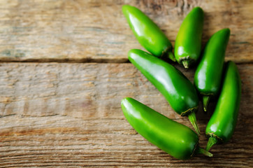 Fresh jalapeno peppers on a dark wood background