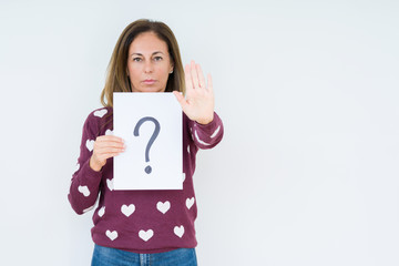 Middle age woman thinking and holding paper with question mark symbol over isolated background with open hand doing stop sign with serious and confident expression, defense gesture