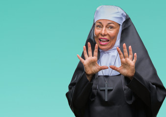 Middle age senior christian catholic nun woman over isolated background afraid and terrified with...