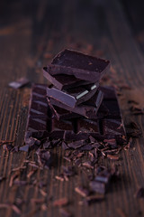 Column of dark or bitter or milk chocolate on a wood background.