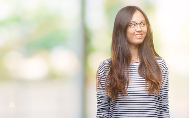 Young asian woman wearing glasses over isolated background smiling looking side and staring away thinking.