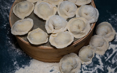 Uncooked dumplings lie on an inverted sieve on the table.