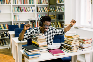 Happy African student sitting at the library table and happy to finish the scientific work