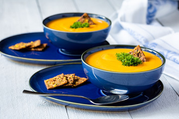 Yellow sauce soup in blue bowls on white wooden table