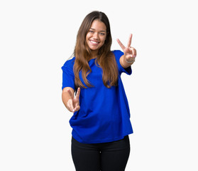 Young beautiful brunette woman wearing blue t-shirt over isolated background smiling looking to the camera showing fingers doing victory sign. Number two.