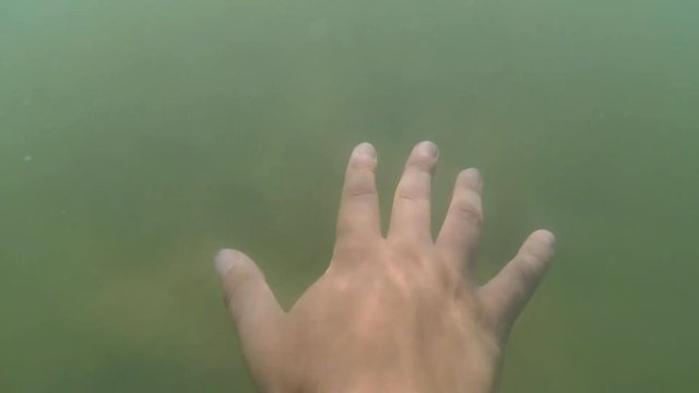 Slow motion POV. Scene point of view the hand glides slides on the surface of the water on a sunny day with natural sunny light rays close-up. Ocean sea summer concept. Top view