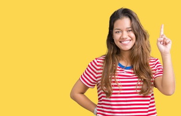 Young beautiful brunette woman wearing stripes t-shirt over isolated background showing and pointing up with finger number one while smiling confident and happy.