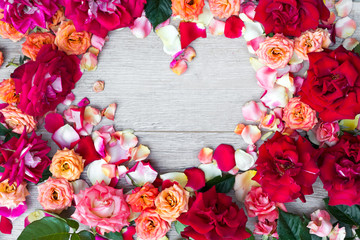 Frame heart made of rose flowers on wooden background for Valentines day. Flat lay, copy space