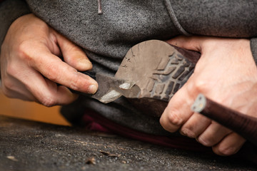 close up of the hands of a man repairing shoes