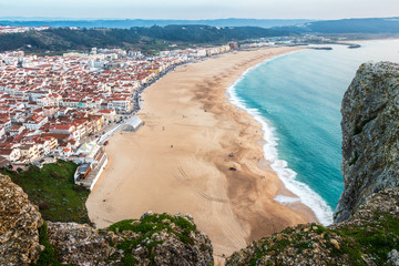 Nazaré beach seen from above, from the viewpoint of the Sítio, with rocks in foreground.