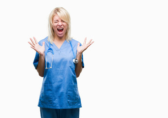 Young beautiful blonde doctor woman wearing medical uniform over isolated background celebrating mad and crazy for success with arms raised and closed eyes screaming excited. Winner concept