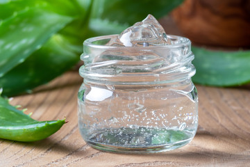 Aloe vera gel in a glass jar, with fresh aloe vera plant in the background