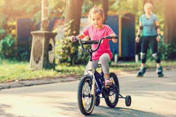 Fototapeta premium Little girl with helmet riding bike at sunset