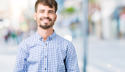 Fototapeta premium Young handsome business man over isolated background Hands together and fingers crossed smiling relaxed and cheerful. Success and optimistic