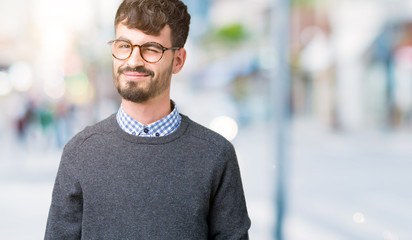 Young handsome smart man wearing glasses over isolated background winking looking at the camera...