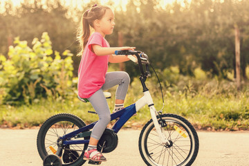 Fototapeta na wymiar Little girl riding bike at sunset