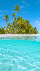 Fototapeta na wymiar HALF UNDERWATER: Crystal clear water splashes over lens filming exotic island.