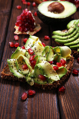 sliced avocado and ripe pomegranates on toast bread with spices and avocado.