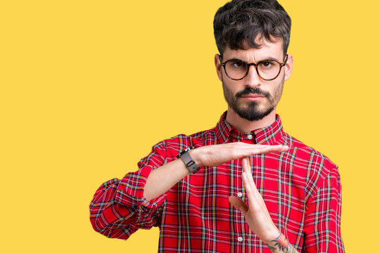 Young handsome man wearing glasses over isolated background Doing time out gesture with hands, frustrated and serious face