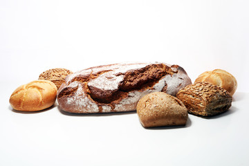 Different kinds of bread and bread rolls on board from above.