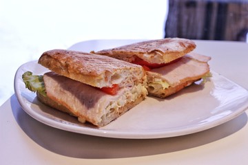 Delicious hot sandwich with turkey, tomatoes, lettuce, sliced, on a plate