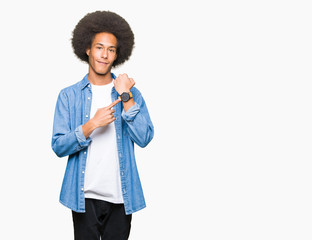 Young african american man with afro hair In hurry pointing to watch time, impatience, upset and angry for deadline delay