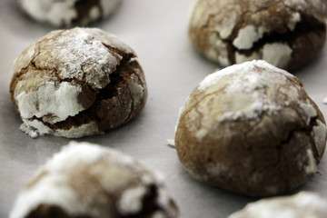 Step-by-Step. Baking homemade chocolate crinkle cookies with powdered sugar icing. Hot fresh cookies on parchment paper.