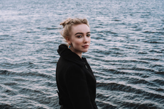 Side view portrait of confident young woman standing by river in city