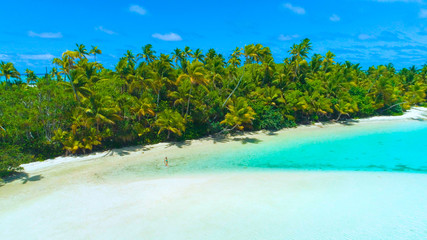 Fototapeta na wymiar DRONE: Tourist girl in bikini walks into the shallow turquoise ocean water.