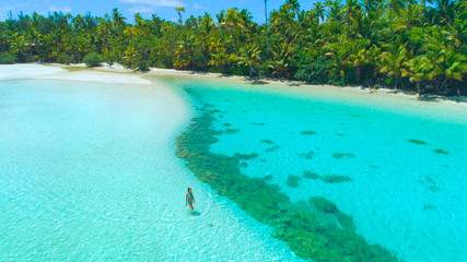 DRONE : Une touriste en bikini se promène dans l& 39 eau turquoise peu profonde de l& 39 océan.