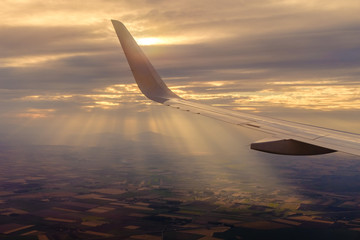 Wing of the plane during the flight with sun rays in the background