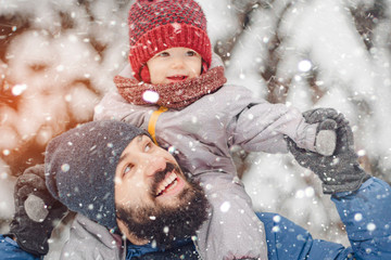 happy father and baby son having fun under sunny winter snow, holiday season.