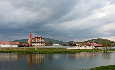View of the houses near river Latoritsa of a small town and dark stormy dramatic clouds background, Mukachevo, Ukraine