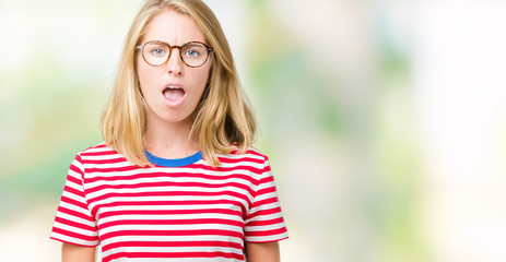Beautiful young woman wearing glasses over isolated background In shock face, looking skeptical and...