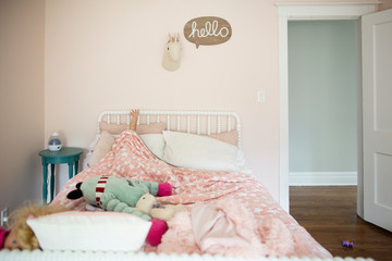 Girl raising hand while lying on bed at home
