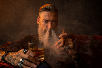 Portrait eines attraktiven Geschäftsmannes mit einer Zigarre und einem Glas Whiskey und viel Rauch...