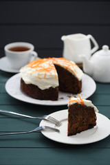 Chocolate fruit cake with cream cheese glasing and orange peel served with black tea on dark background