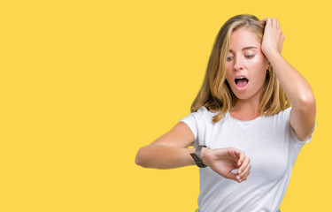 Beautiful young woman wearing casual white t-shirt over isolated background Looking at the watch time worried, afraid of getting late